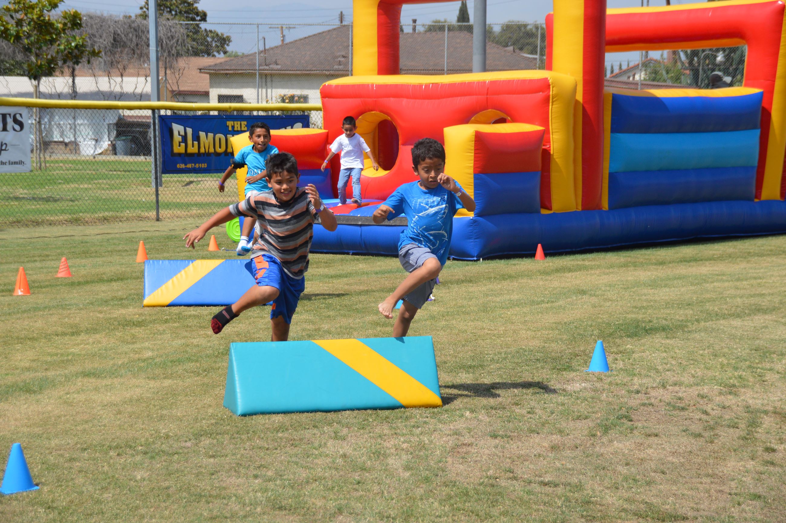 Two kids jumping over an obstacle at the Red, White and Bounce! Health & Wellness Fair